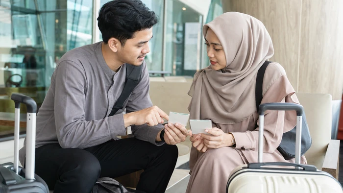 Dua calon jamaah Indonesia menyiapkan komunikasi untuk perjalanan umrah mandiri di area transit