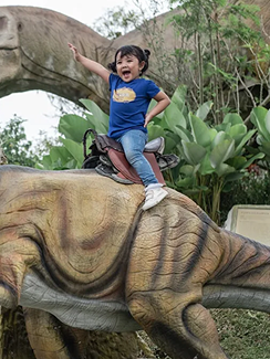 Anak Naik Patung Dinosaurus