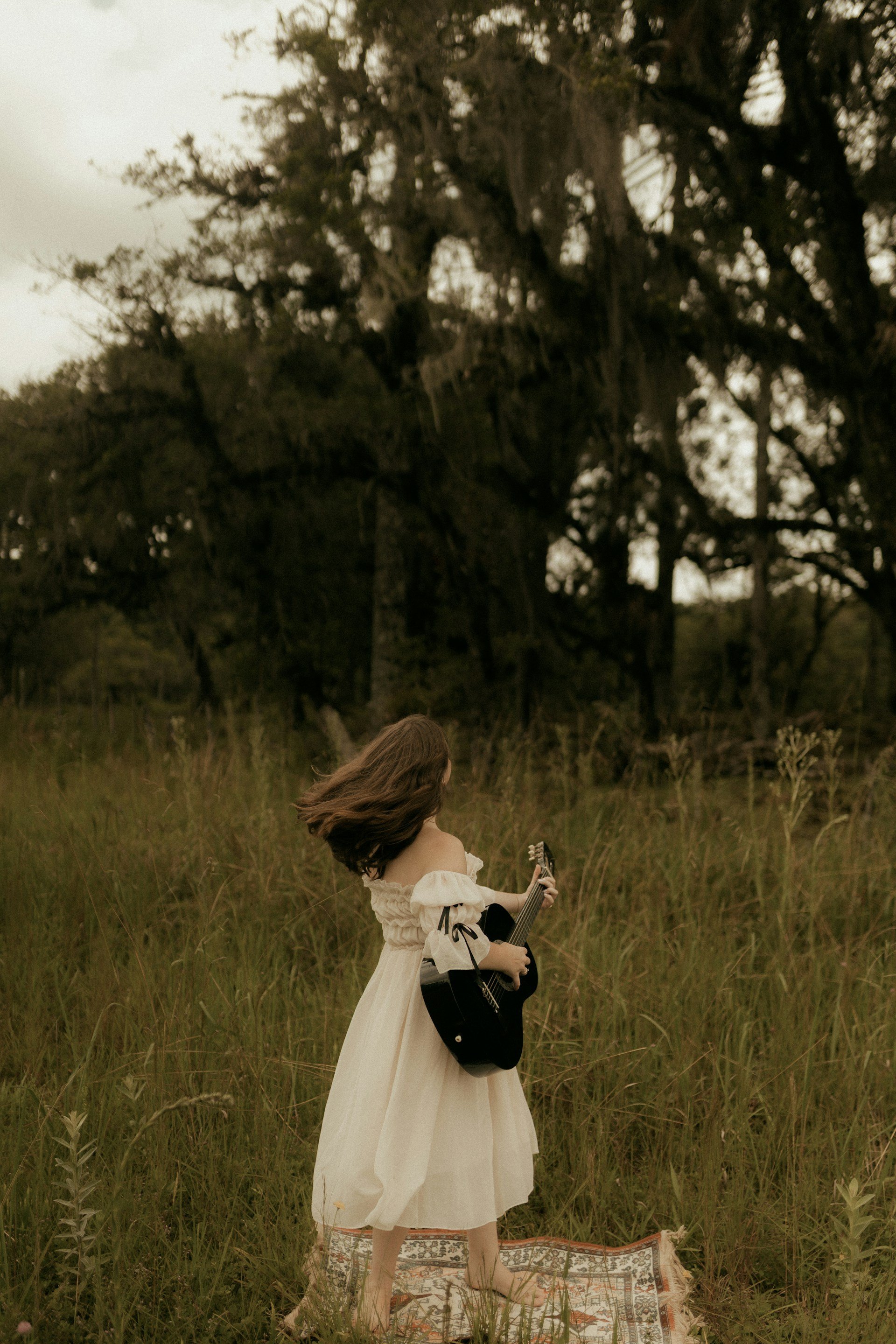 A woman dressed in white lying in tall grass.