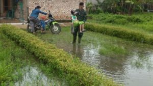 Personil Satgas TMMD Gendong Anak Untuk Melintasi Genangan Banjir